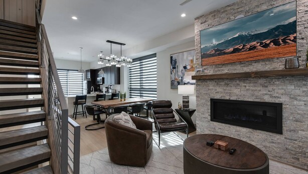 A modern living room with a fireplace, a dining area, and a kitchen in the background.