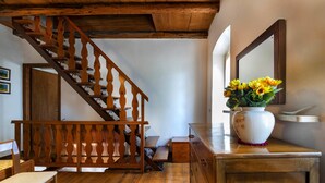 A wooden staircase with a railing, a wooden bench, a wooden dresser, and a vase with flowers.