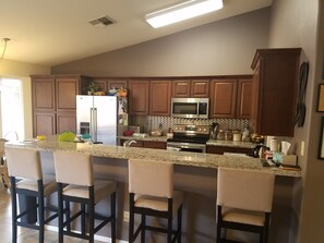 A kitchen with wooden cabinets, a stainless steel refrigerator, a microwave, an oven, and a granite countertop.