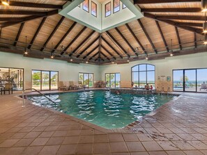 An indoor swimming pool with a high ceiling and large windows.