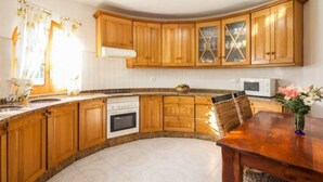 A kitchen with wooden cabinets, a built-in oven, and a dining table with chairs.