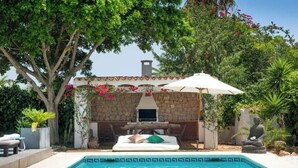 A pool area with a stone wall, outdoor seating, and a statue.