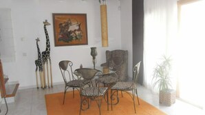 A dining area with a table and chairs, a giraffe sculpture, a painting, and a hanging light fixture.