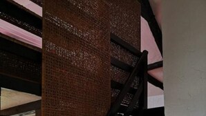 Eine Treppe mit einem gewobenen Kopfteil, ein Fenster mit Blick nach außen und ein Heizkörper darunter.