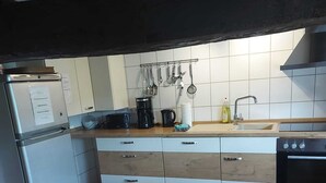 Eine kleine Küche mit Kühlschrank, Kaffeemaschine, Spüle und Herd.