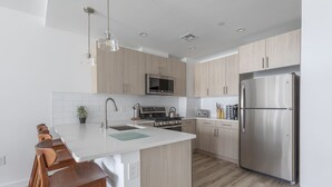 A modern kitchen with a central island, stainless steel appliances, and wooden cabinetry.