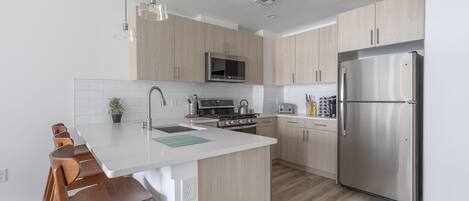 Una cocina moderna con una isla central, electrodomésticos de acero inoxidable y muebles de madera.