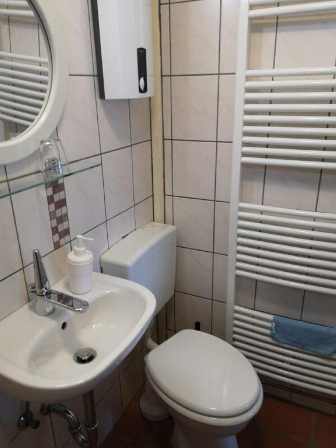 A bathroom with a white sink, toilet, and a towel rack.