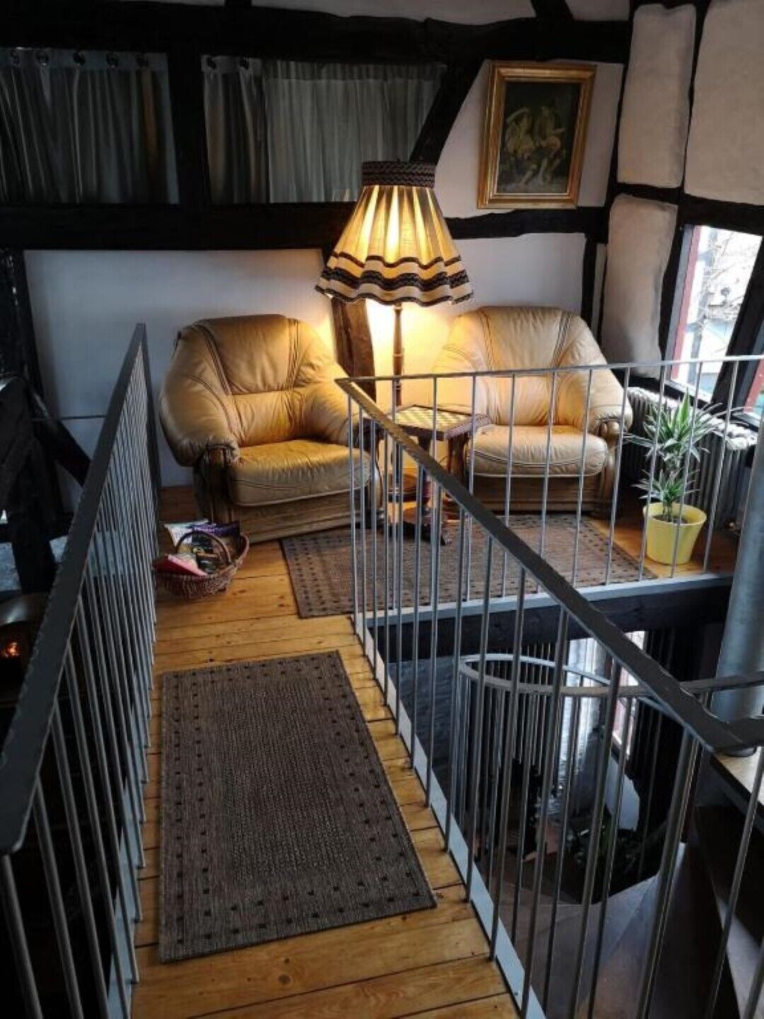 Ein gemütliches Wohnzimmer mit einer Couch, einer Lampe und einer Treppe.