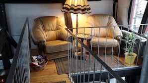 Un salon confortable avec un canapé, une lampe et un escalier.