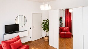 A modern living room with a TV, red sofa, and a potted plant.