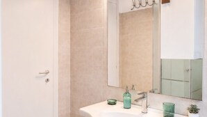 A bathroom with a white sink, mirror, and cabinets.