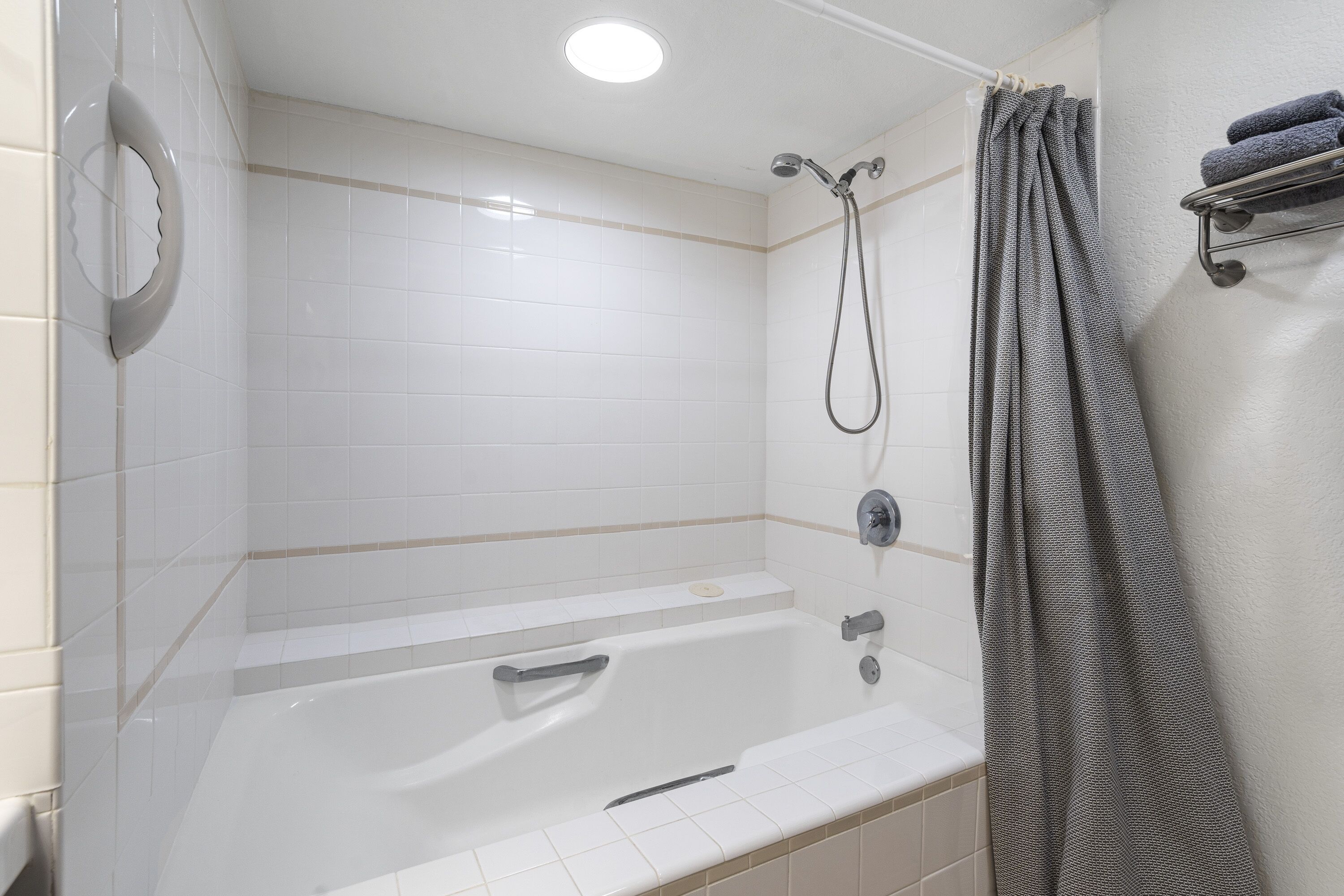A modern bathroom with a bathtub, shower, and a towel rack.