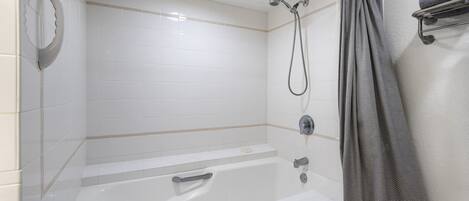 A modern bathroom with a bathtub, shower, and a towel rack.