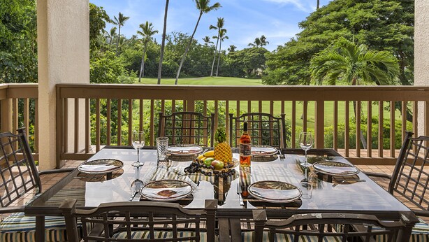 Mesa de comedor preparada para seis personas, con vista a un paisaje tropical que incluye palmeras y un campo de golf.