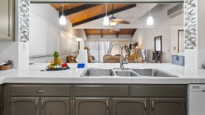 Una cocina con una isla grande, dos fregaderos y un ventilador de techo.