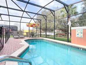 An indoor swimming pool with a covered area, chairs, and a table.