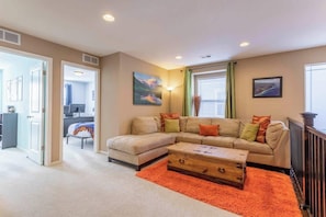 A living room with a sofa, coffee table, and artwork on the walls. - Spacious Family Friendly Townhome in Central Park (Denver)