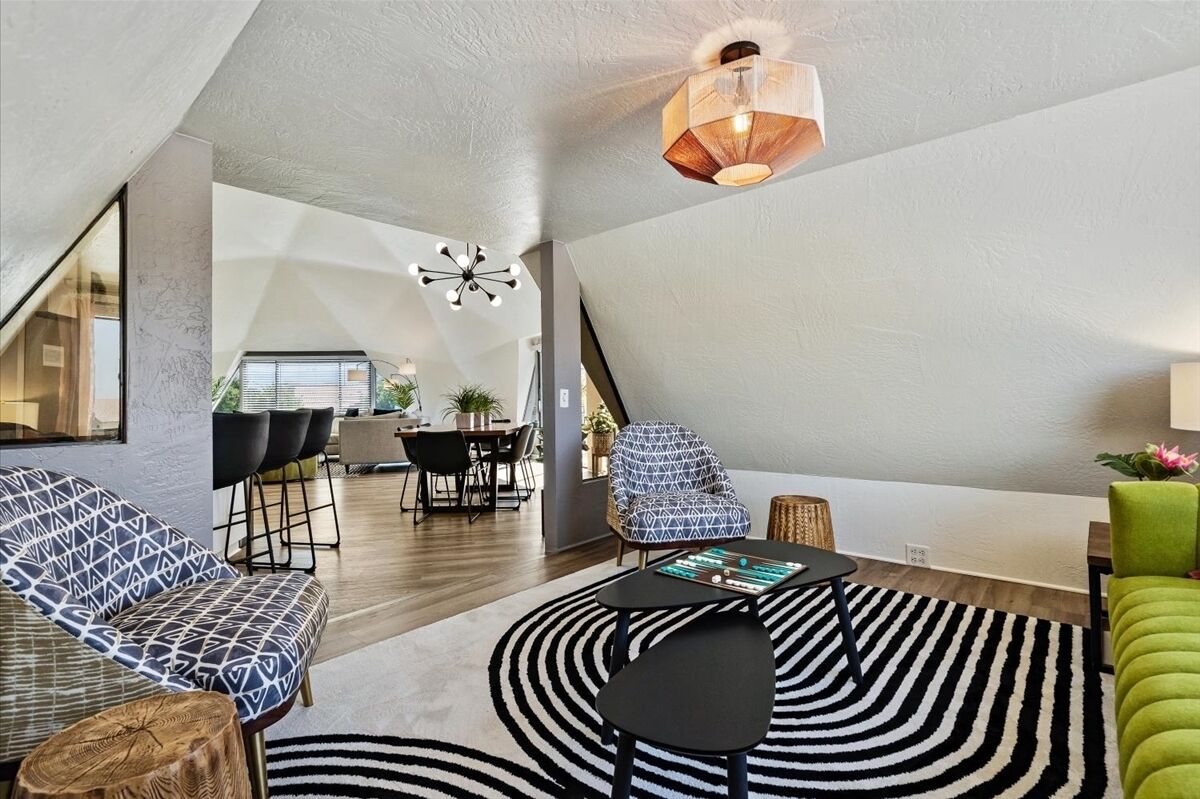 Un loft moderno con comedor, sala de estar con alfombra a rayas negras y blancas y un sillón verde.