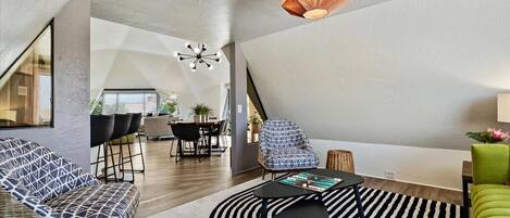 Un loft moderno con comedor, sala de estar con alfombra a rayas negras y blancas y un sillón verde.