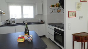 A modern kitchen with white cabinets, a black countertop, and a built-in oven. - Holiday Home in Paimpol near Beaches (Paimpol)