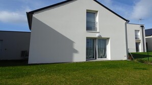 A modern two-story house with a flat roof, a large window with curtains, and a small balcony. - Holiday Home in Paimpol near Beaches (Paimpol)