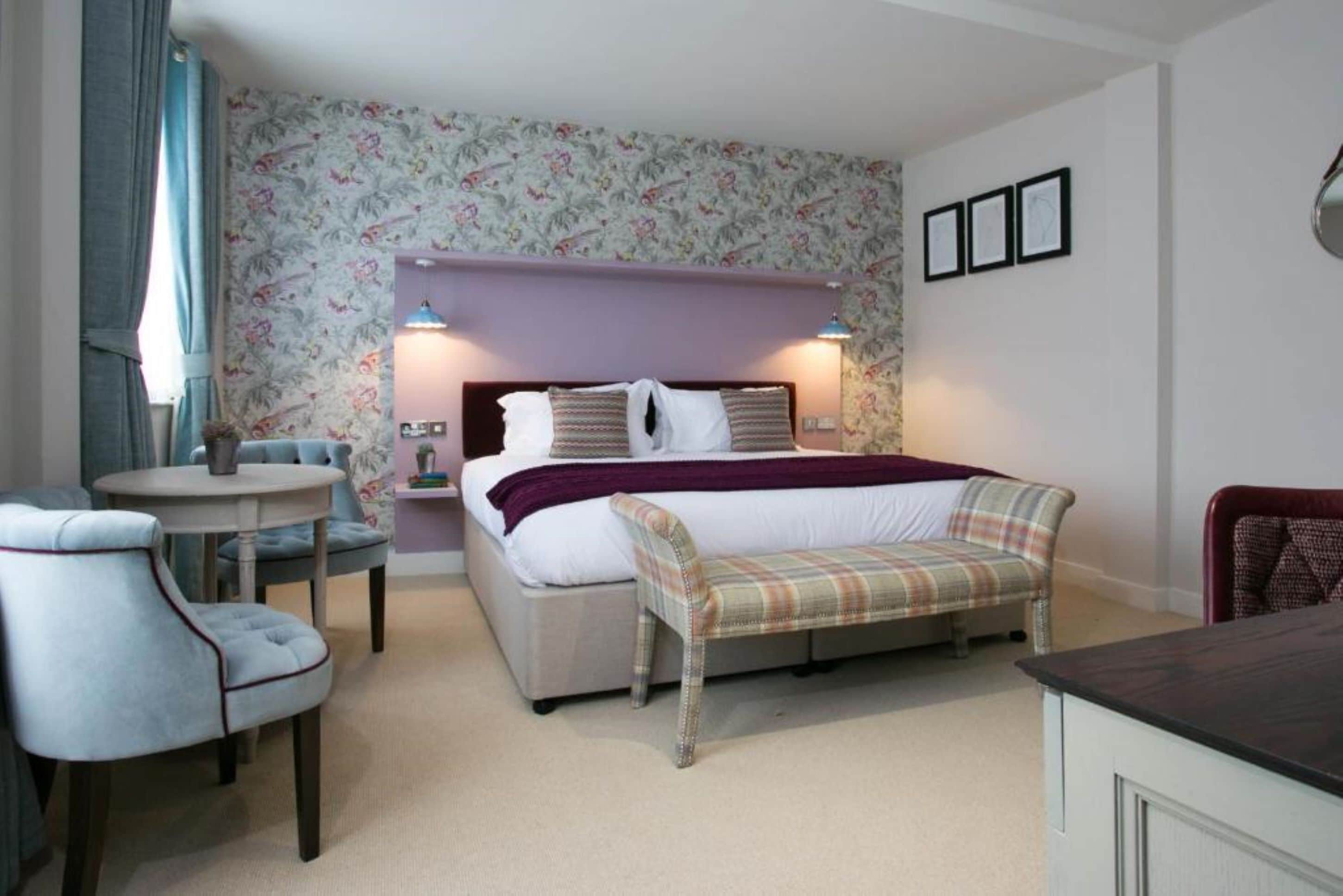 A bedroom with a bed, bedside tables, a chair, a bench, and a small table.
