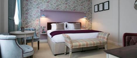 A bedroom with a bed, bedside tables, a chair, a bench, and a small table.