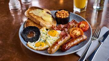 Un plato de desayuno con huevos, tocino, salchichas, tostadas, frijoles y tomates.