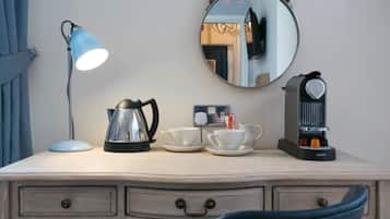 Een houten bureau met een lamp, een koffiezetapparaat en kopjes.