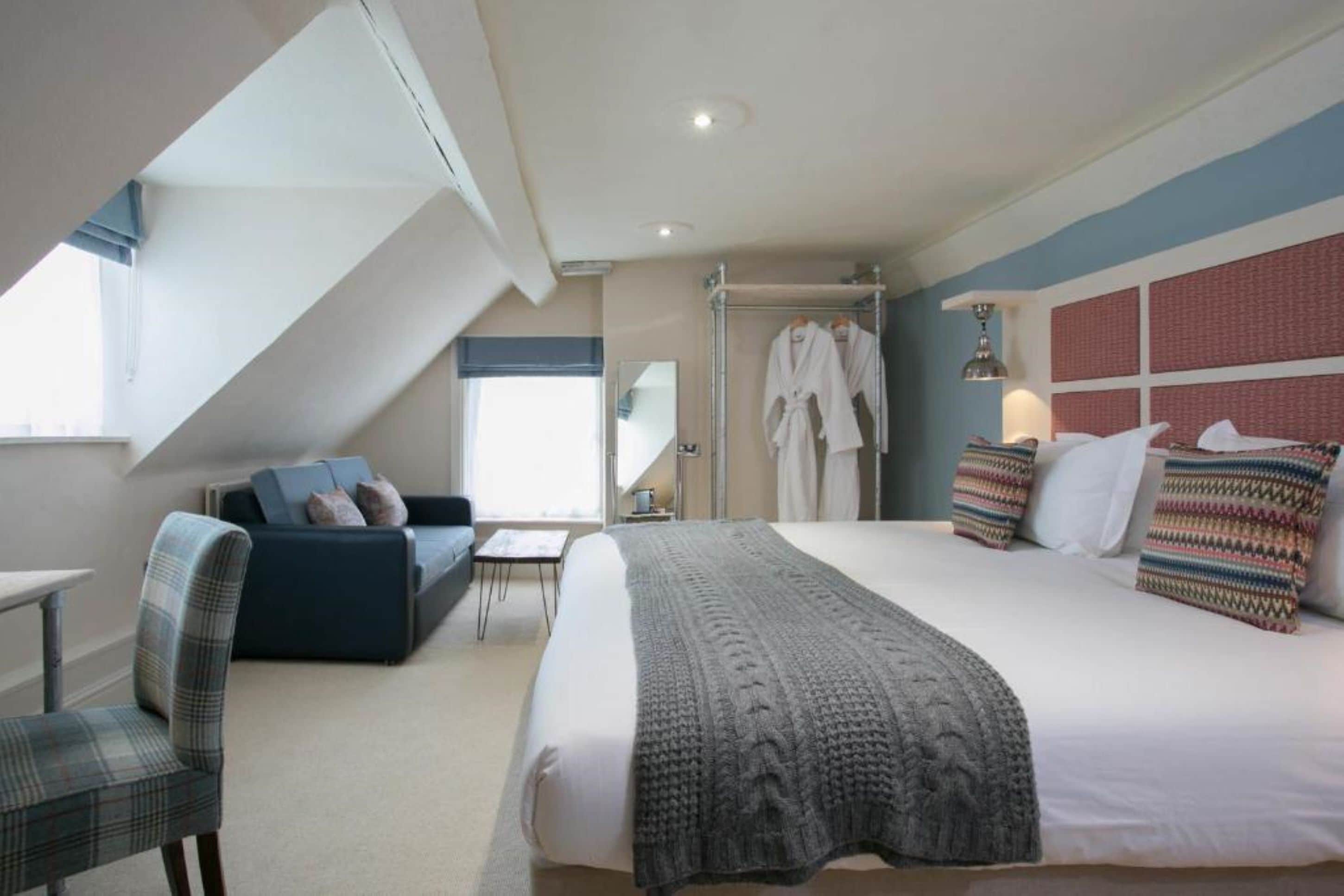 Una habitación de hotel con cama, sofá, silla, mesa y ventana.