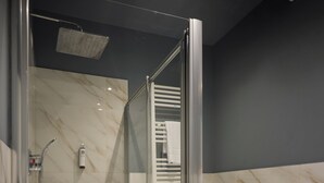 Et moderne badeværelse med et glasafskærmet brusebad, et fritstående badekar og et toilet.
