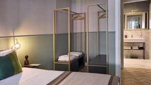 Et hotelværelse med en seng, et natbord med lampe, et garderobeskab med spejl og et badeværelse med håndvask og spejl.