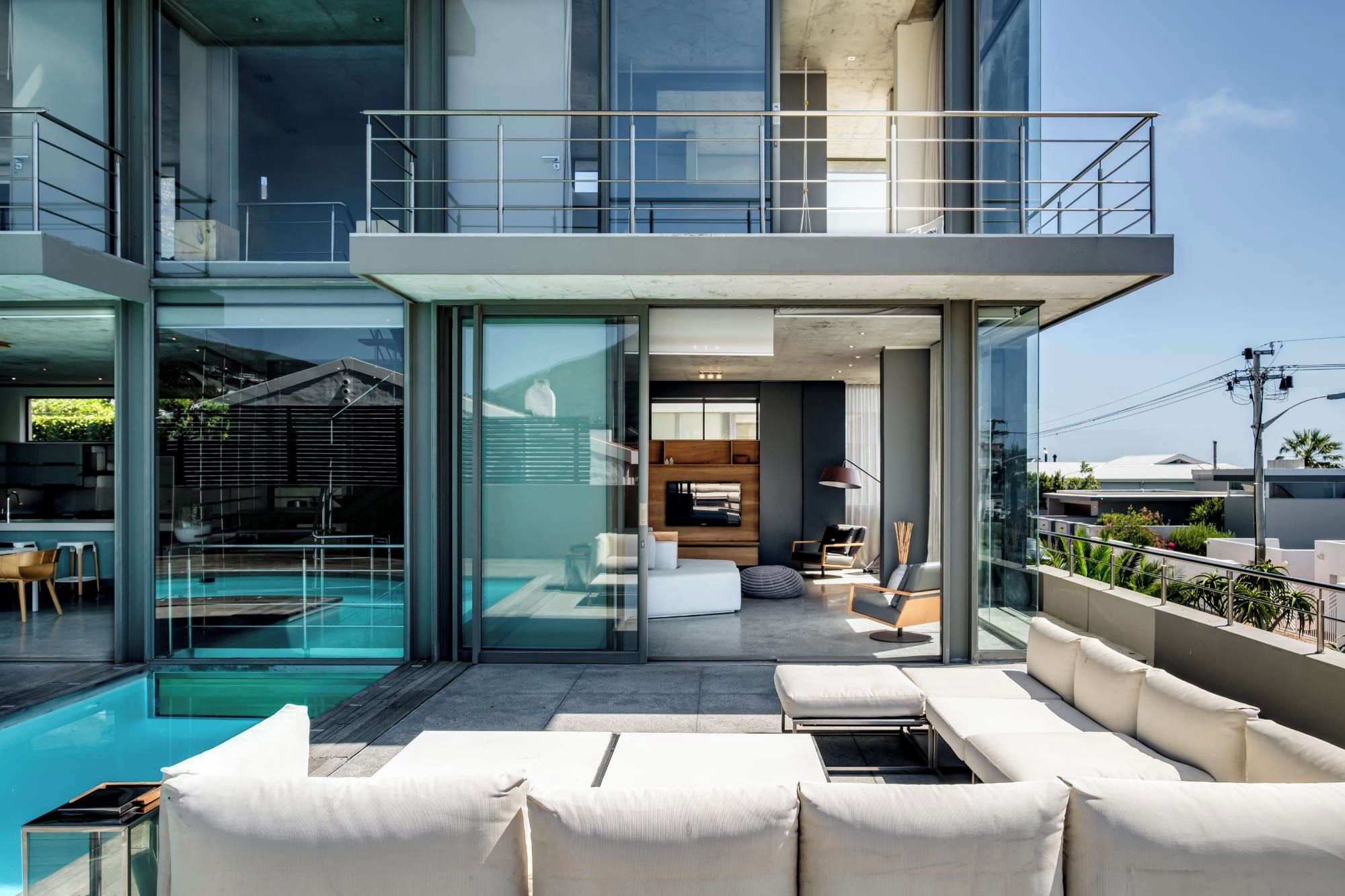A modern residential building with a glass facade, a rooftop pool, and outdoor seating.