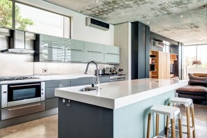A modern kitchen with a central island, stainless steel appliances, and a large window.