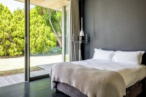 A bedroom with a bed, a window, and a view of trees.