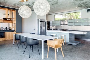 A modern kitchen with a large island, stainless steel appliances, and a dining area with a white table and chairs.