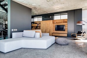 A modern living room with a sectional sofa, a TV, and a dining area with wooden cabinets.