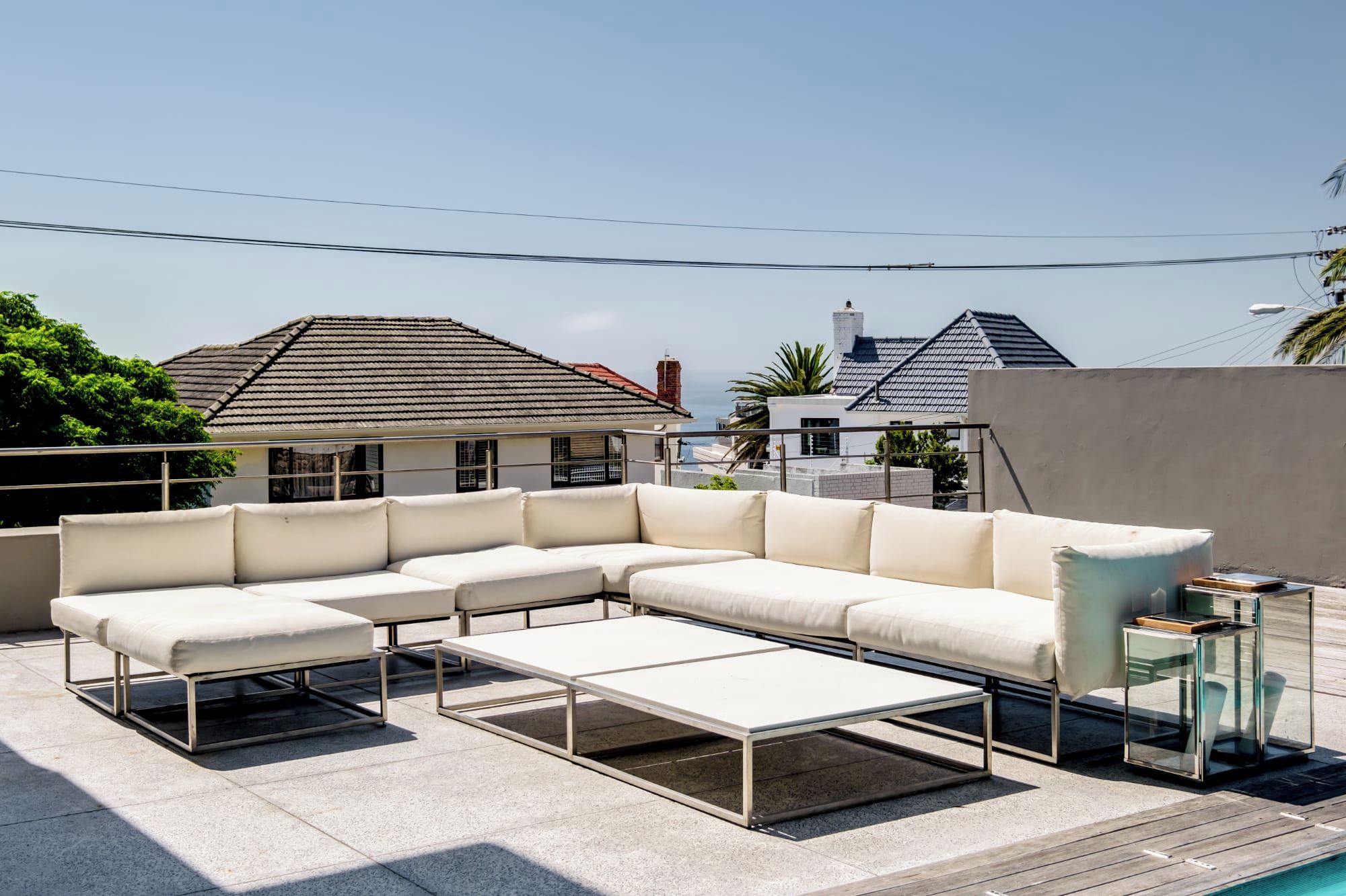 Terraço no telhado com sofá em seção, mesa de centro e mesa lateral.