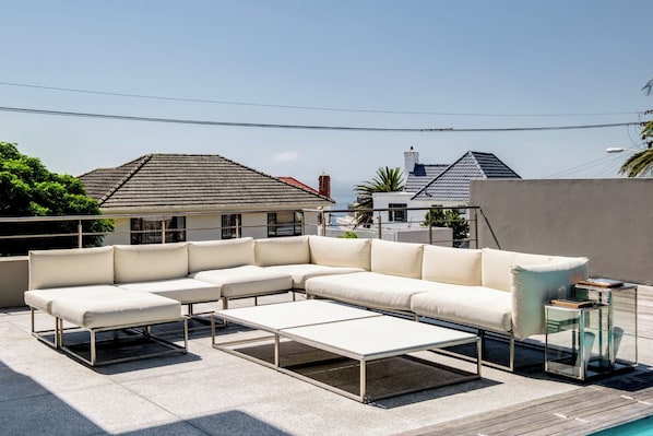A rooftop terrace with a sectional sofa, a coffee table, and a side table.