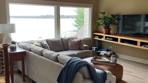 Un salon avec une grande fenêtre, un canapé, une table basse, un téléviseur et une plante.