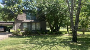 Une maison d’habitation avec un jardin devant, une allée et un VUS garé.