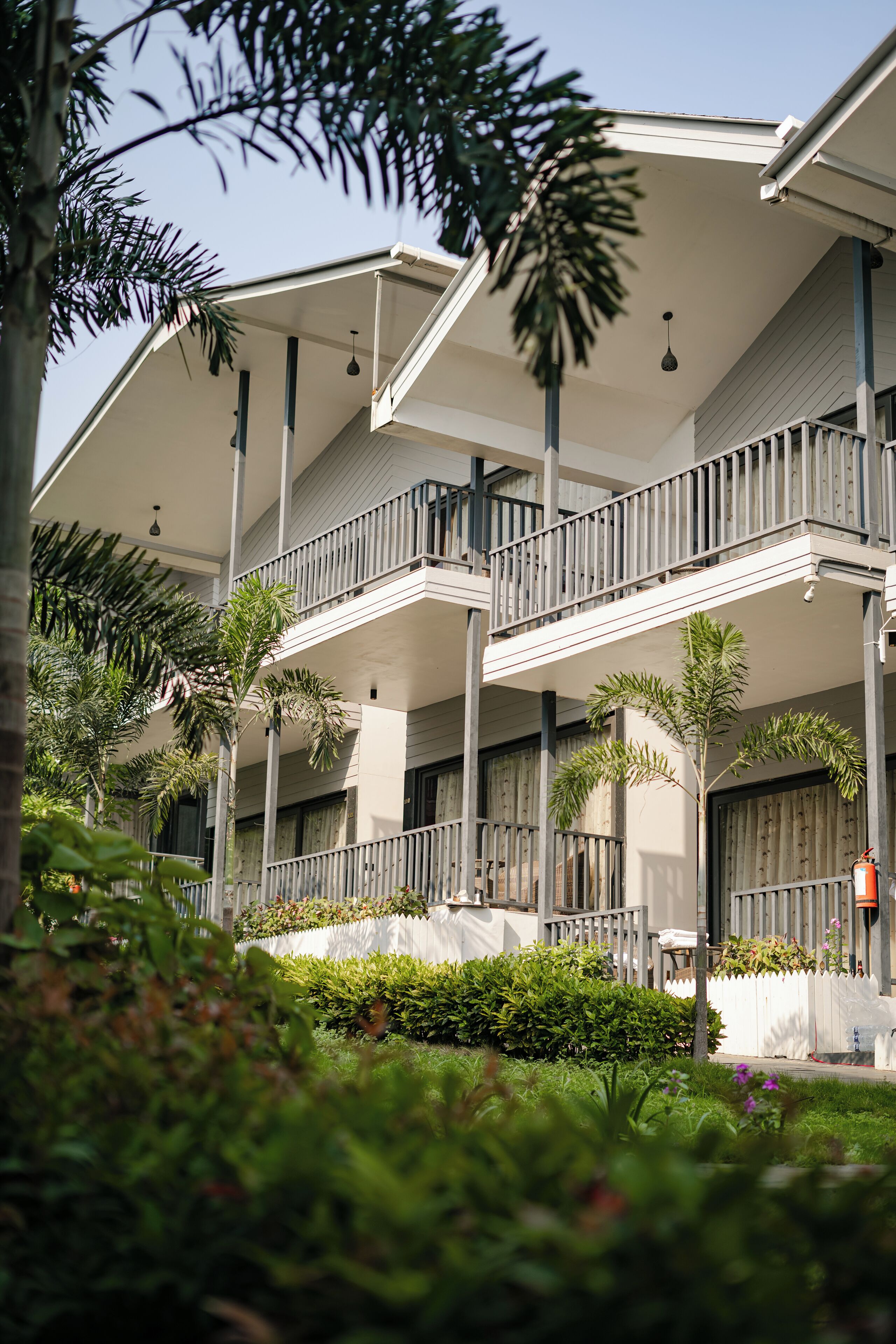 A multi-story hotel with balconies, surrounded by greenery and palm trees.
