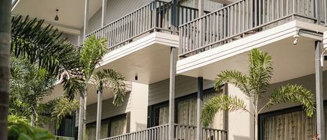 A multi-story hotel with balconies, surrounded by greenery and palm trees.