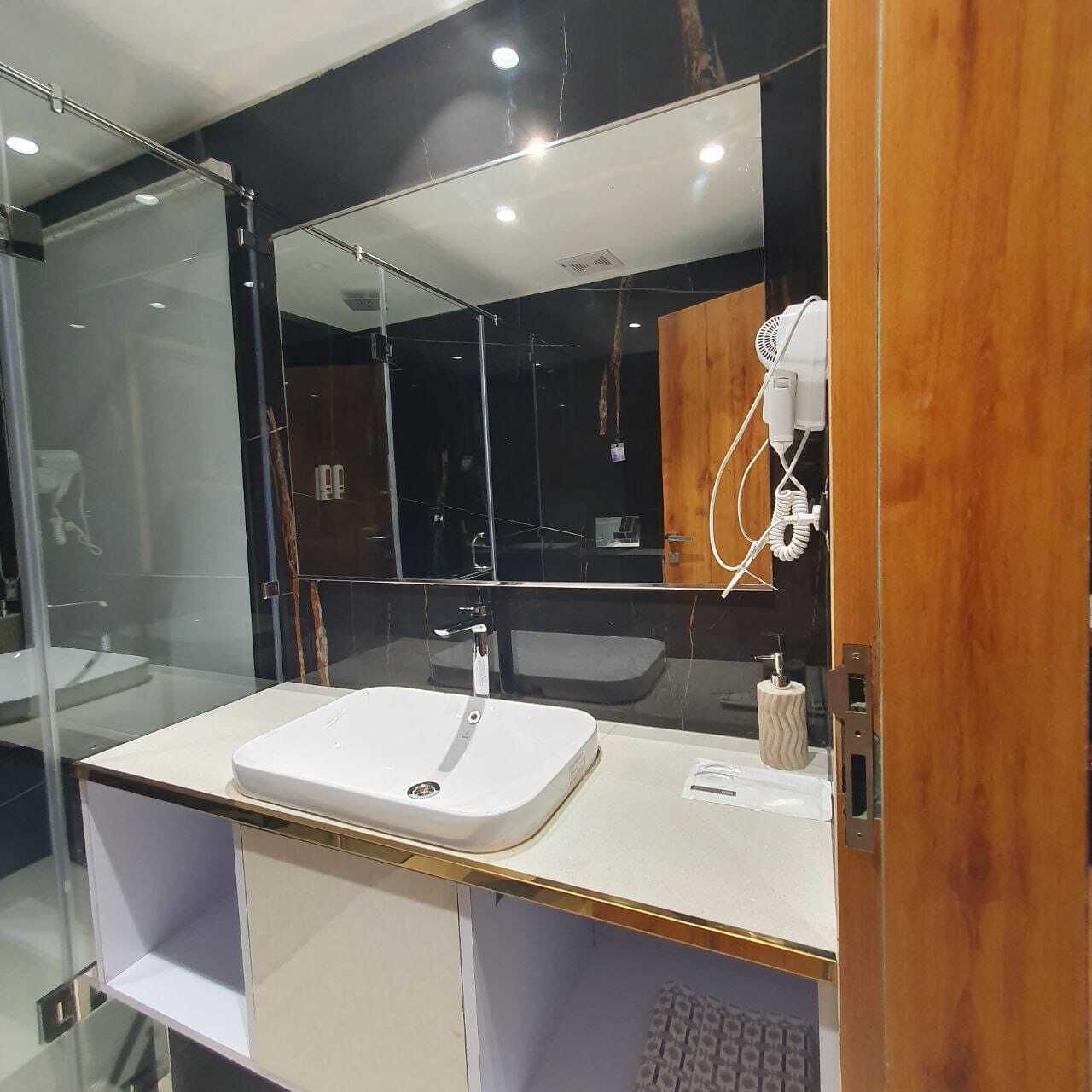 Une salle de bain moderne avec un grand miroir, un lavabo blanc et un porte-serviettes.