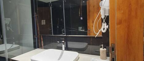 Une salle de bain moderne avec un grand miroir, un lavabo blanc et un porte-serviettes.