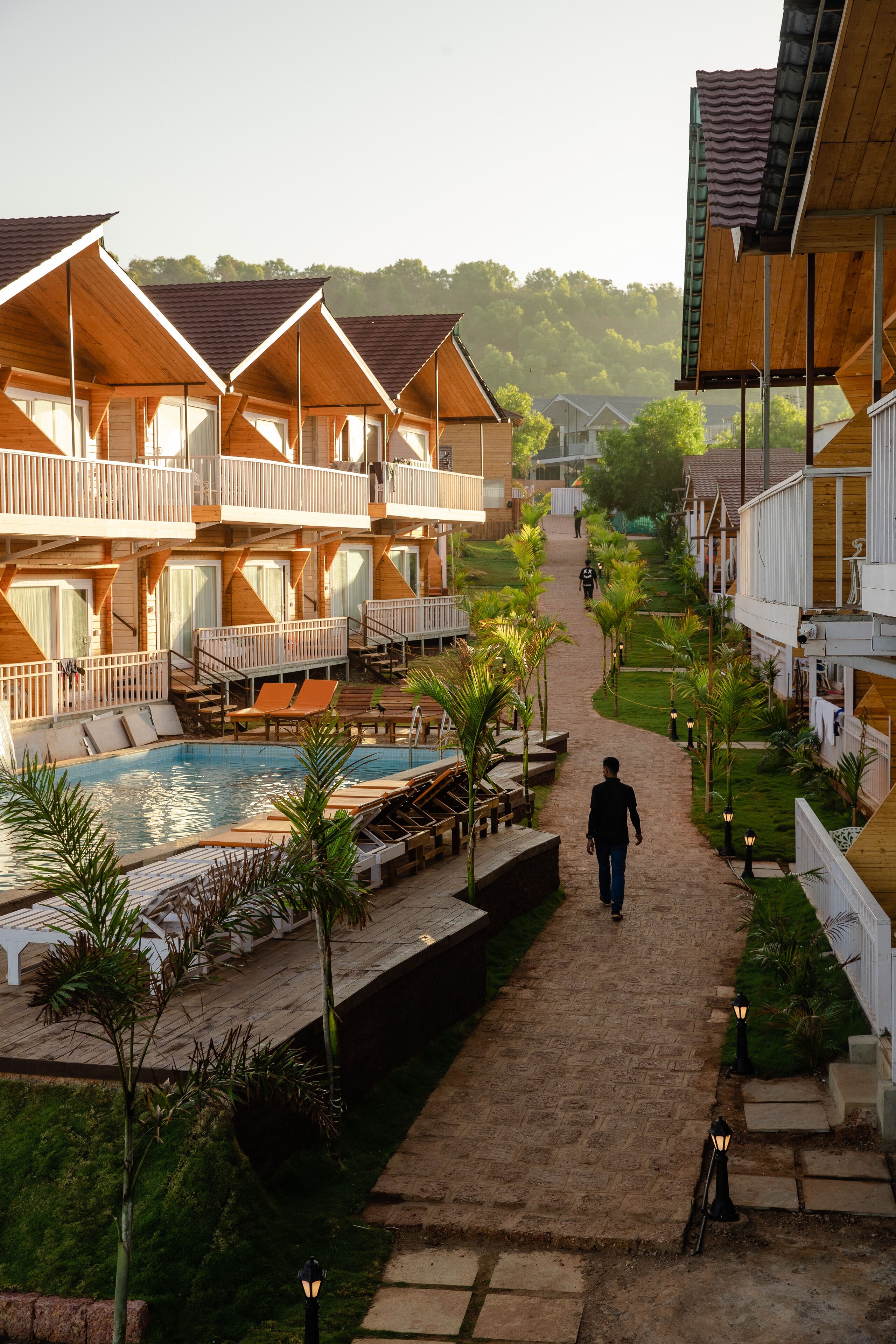 Ein Resort mit mehreren Holzbauten, einem zentralen Poolbereich und einem Weg zu den Gebäuden.
