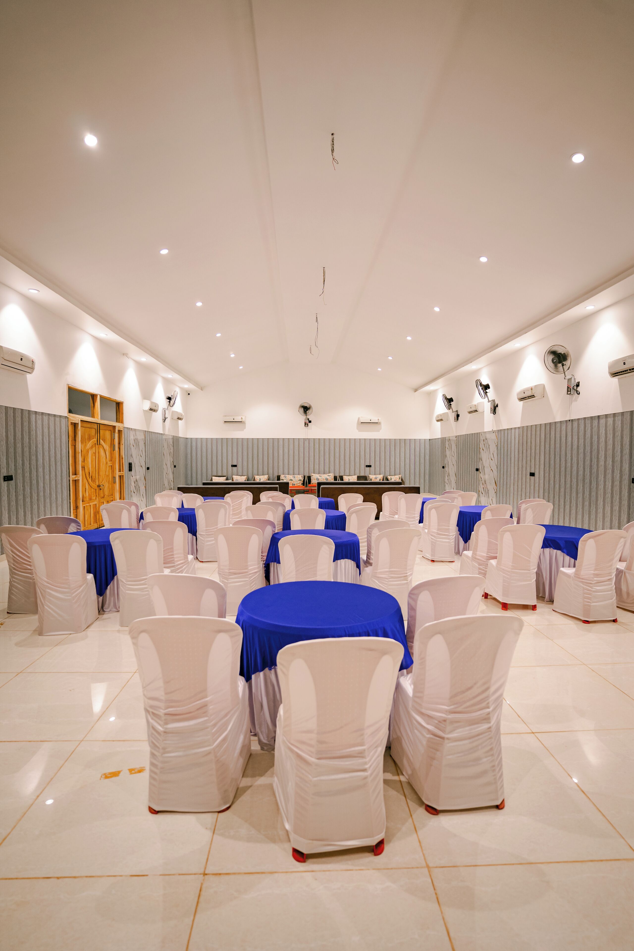 A conference room with tables and chairs, a podium, and a large mirror on the wall.
