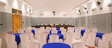 A conference room with tables and chairs, a podium, and a large mirror on the wall.