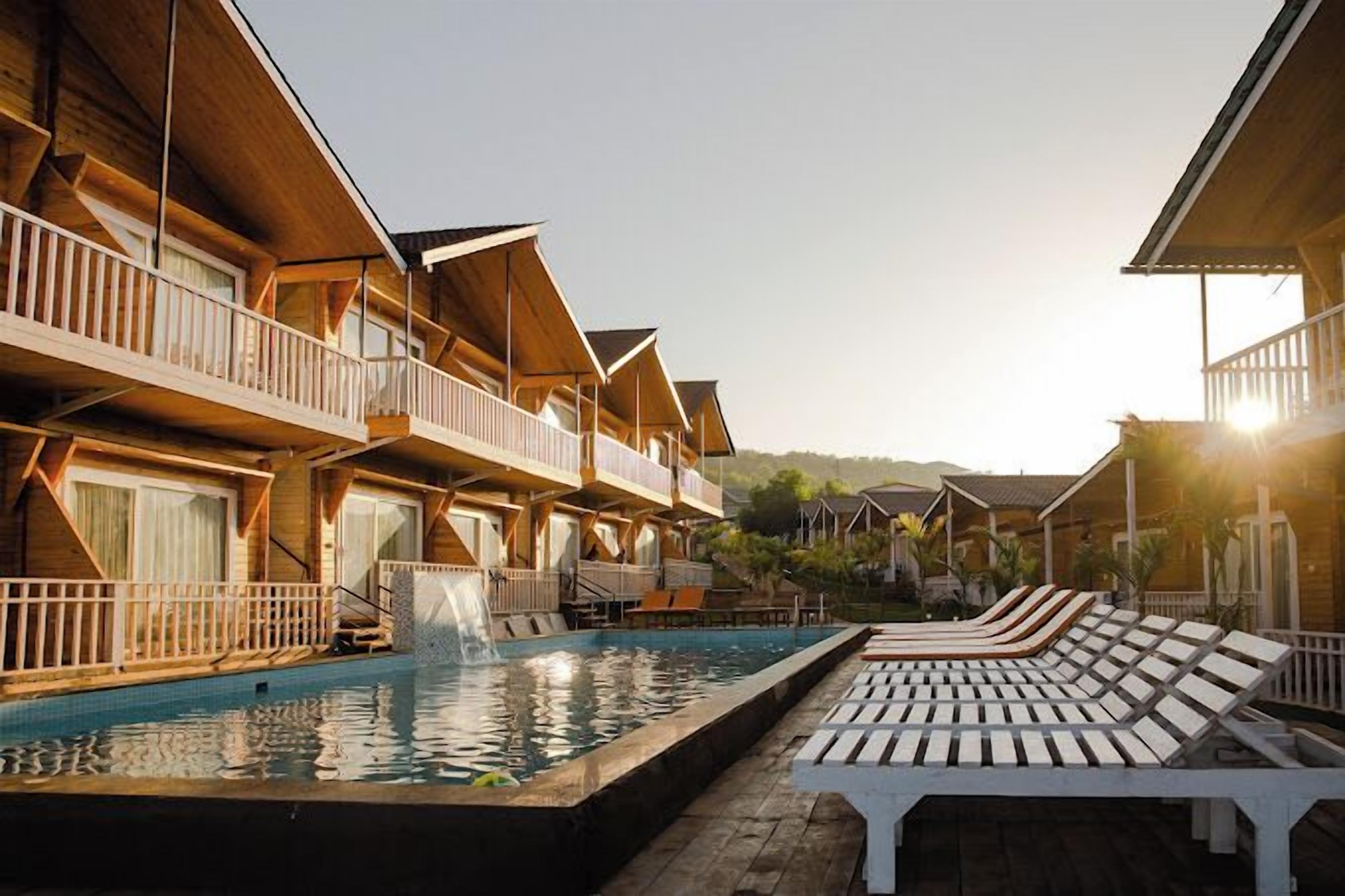 Un resort con edifici in legno, una piscina e lettini da relax.